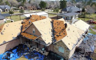 Roofers working on a house roof with new shingles and roofing materials.