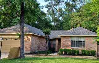 Roofing installation on a brick residential house with a gray shingle roof.