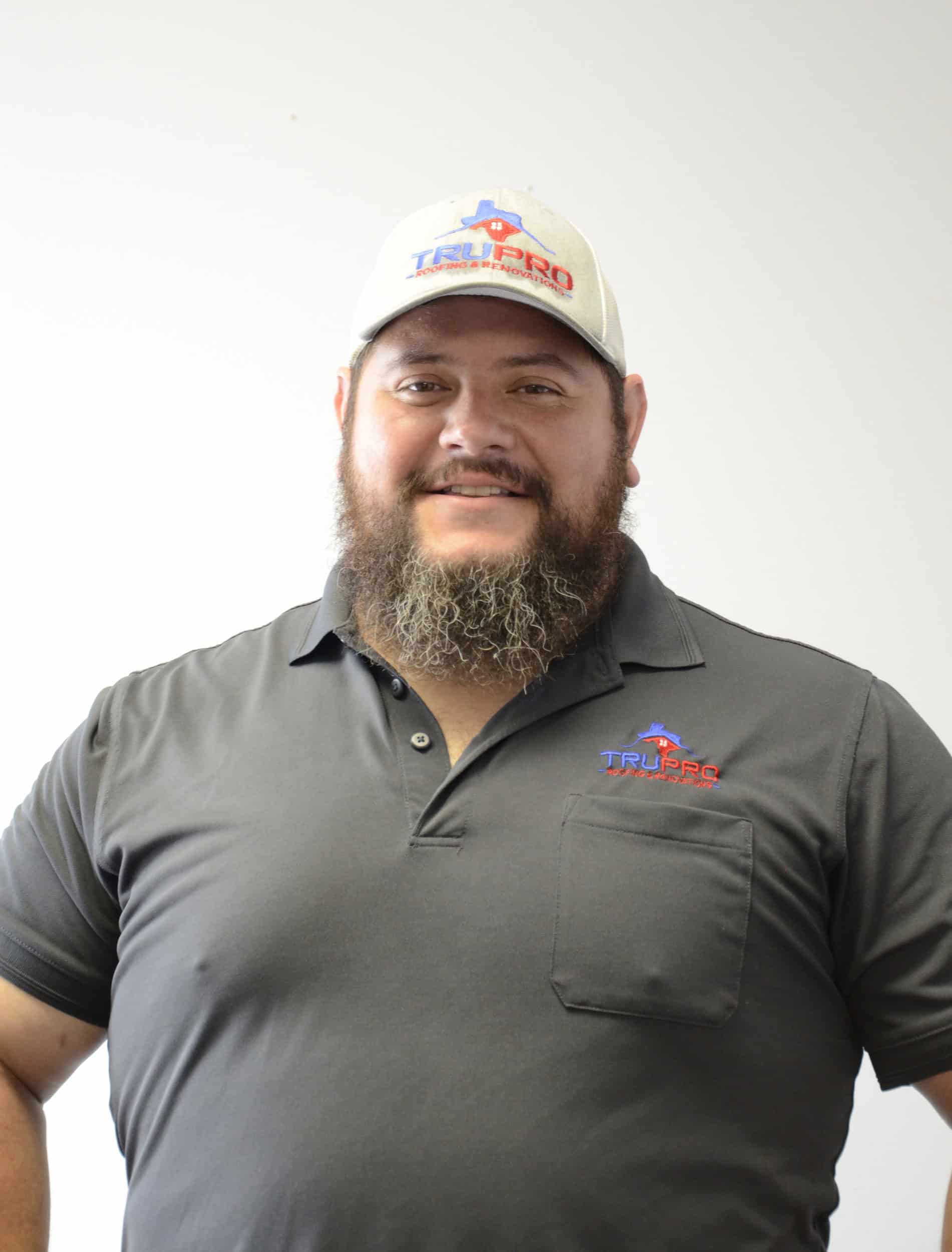 Roofing professional wearing TruPro cap and shirt, smiling confidently.