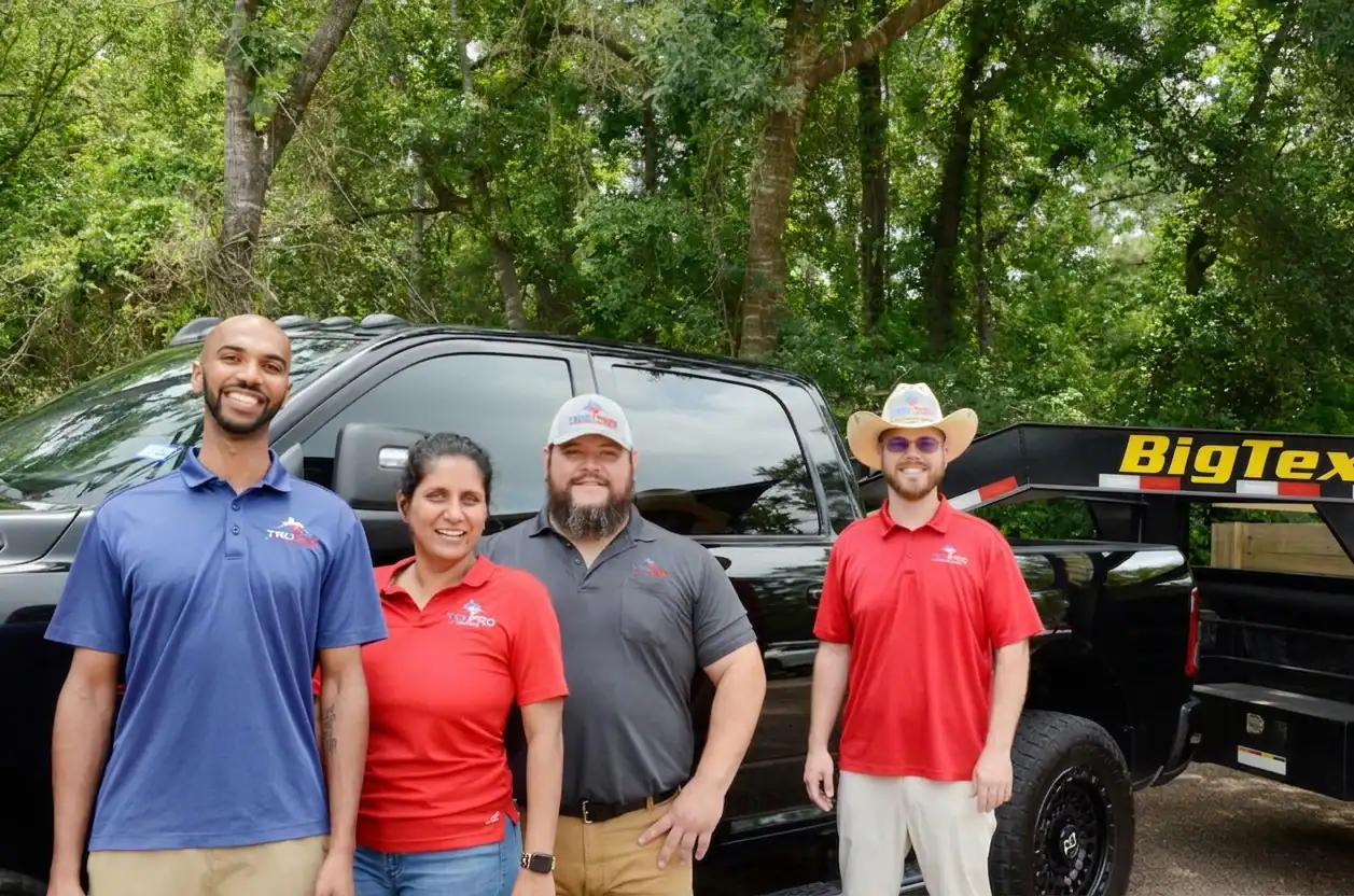 Roofers standing in front of a black truck with a Big Tex trailer, outdoors with trees in the background.